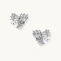 Pair of sculptural white gold-plated stud earrings with twisted ribbon design and sparkling zirconia stones on cream background