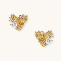 Pair of sculptural gold-plated wing stud earrings with zirconia stones on cream background, showing dimensional feather design