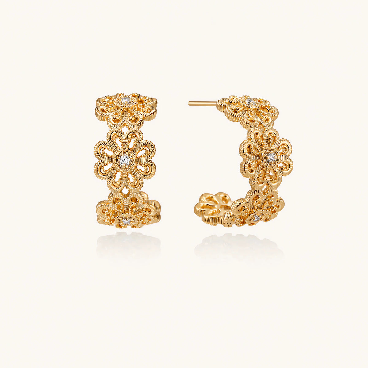 Gold hoop earrings with intricate three-dimensional floral filigree pattern in 14K gold plated brass on cream background